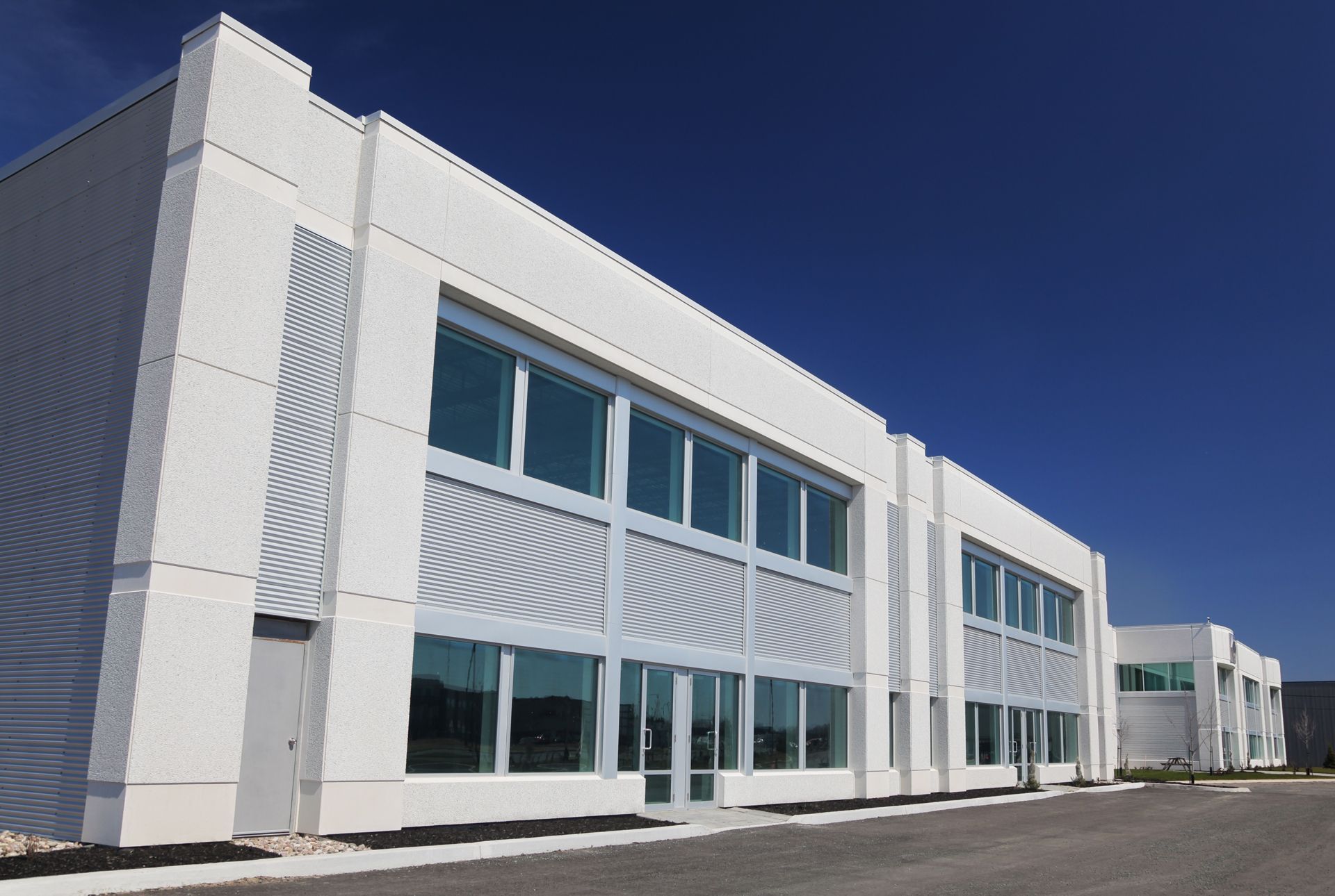 Modern white office building with large windows under a clear blue sky