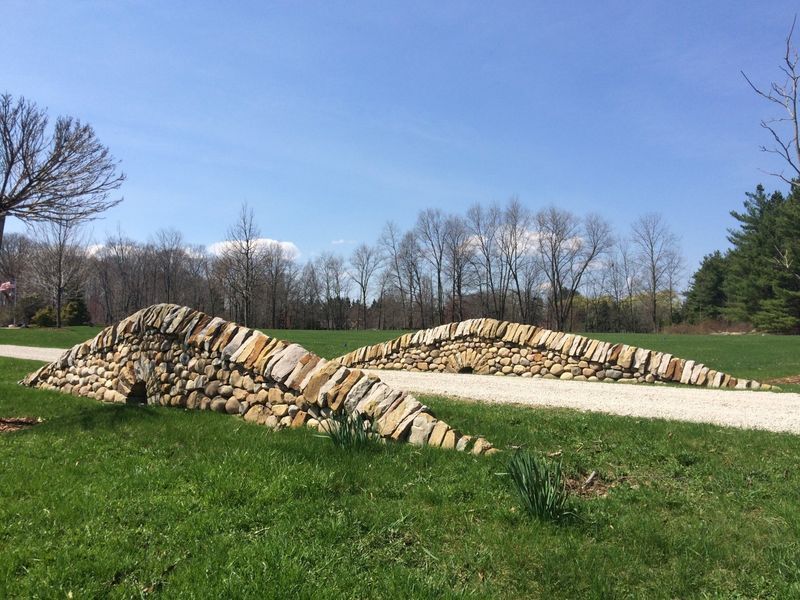 A large rock sculpture is sitting in the middle of a grassy field.