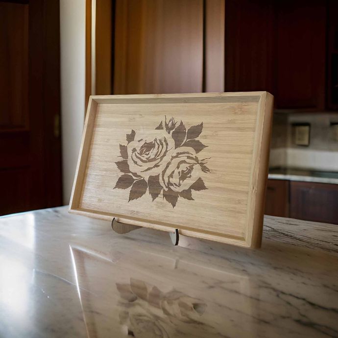 A wooden tray with two roses on it is sitting on a counter.