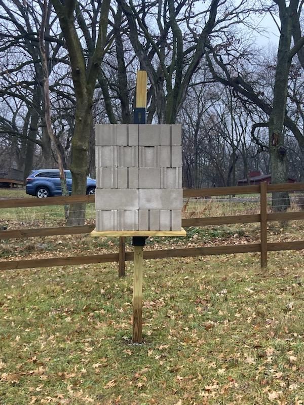 A brick wall is sitting on top of a wooden post in a field.