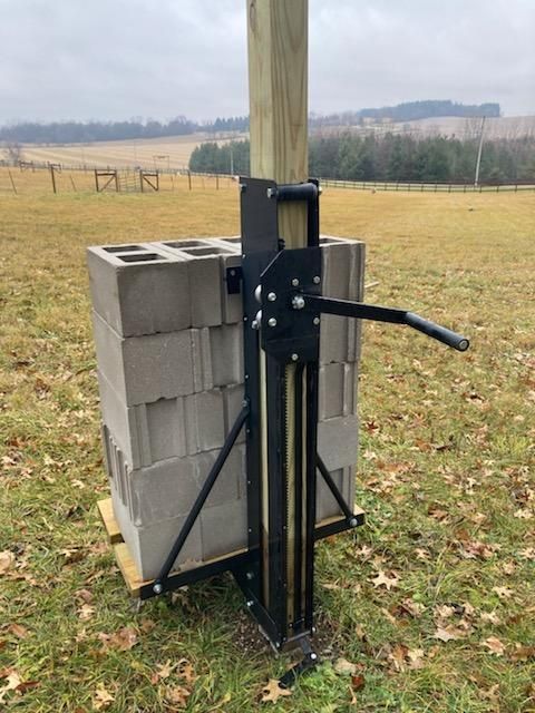 A wooden post is sitting on top of a pile of bricks in a field.
