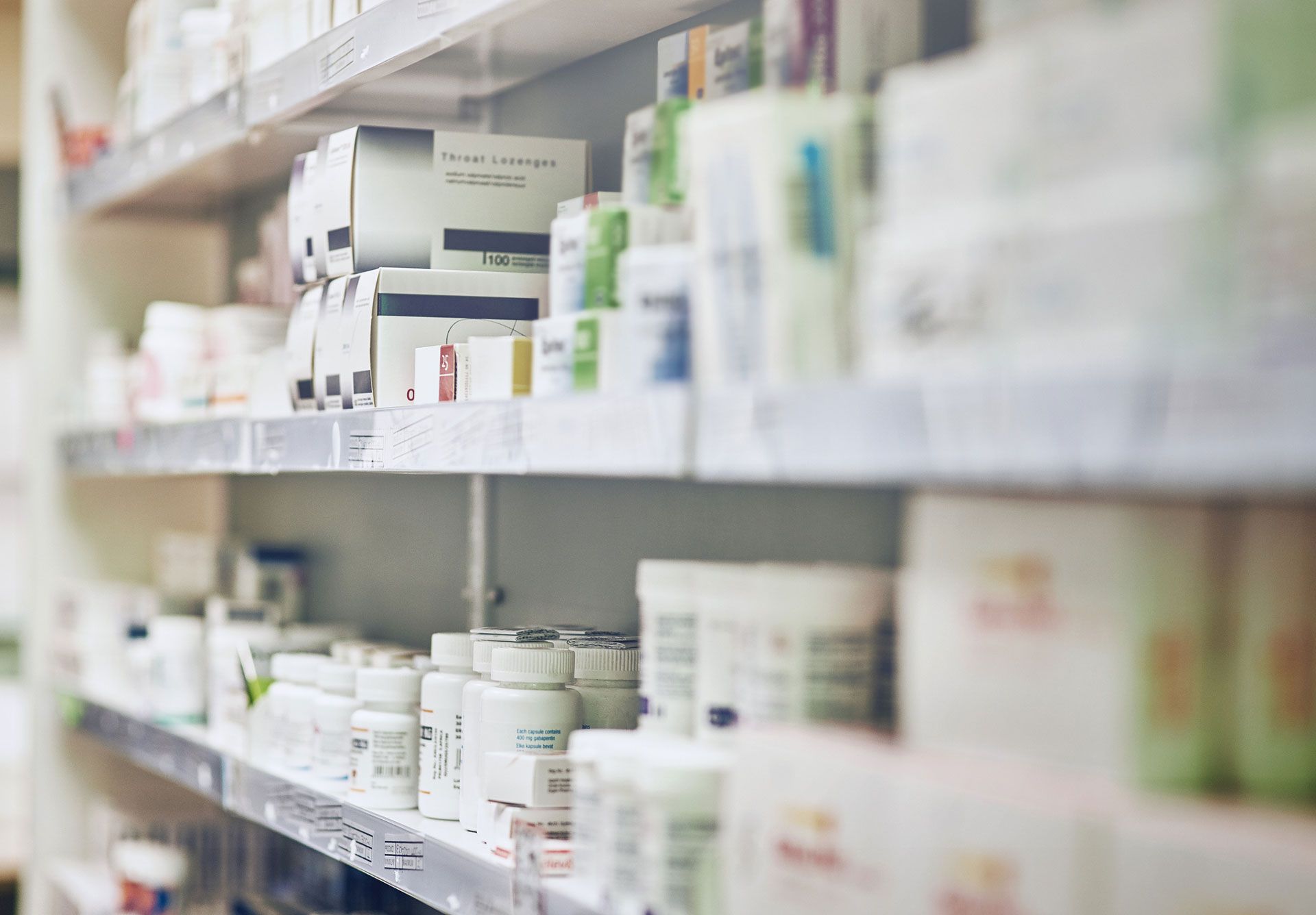 A pharmacy shelf filled with lots of bottles and boxes of medication.