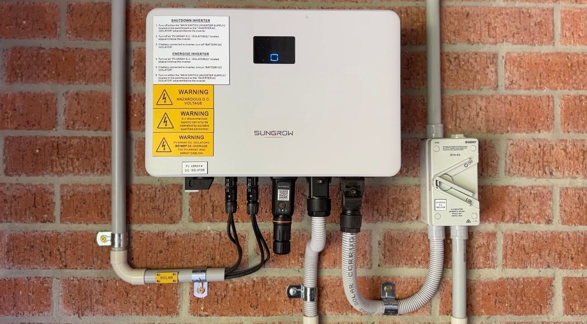 A solar inverter is mounted on a brick wall.