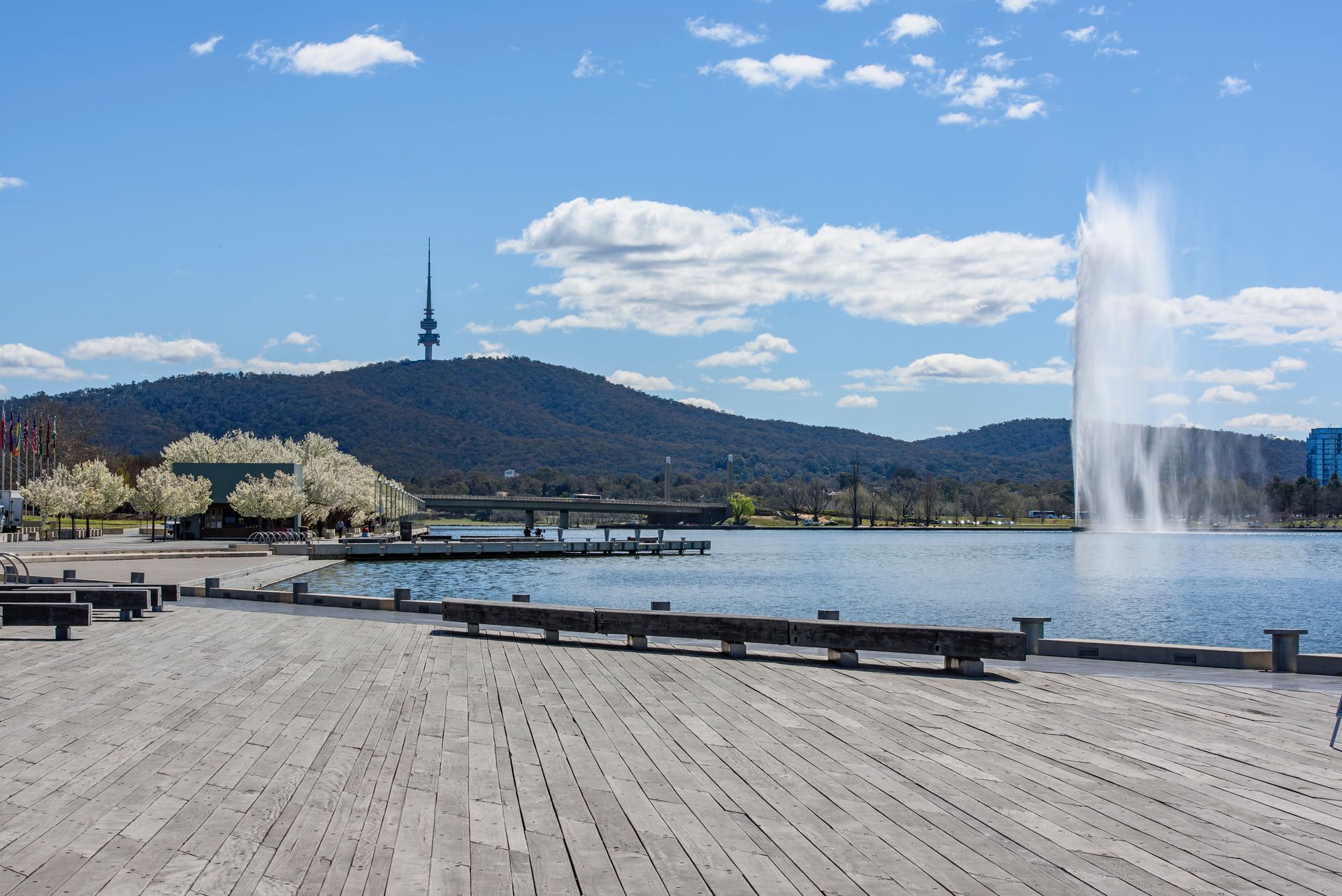 There is a fountain in the middle of a lake with mountains in the background.