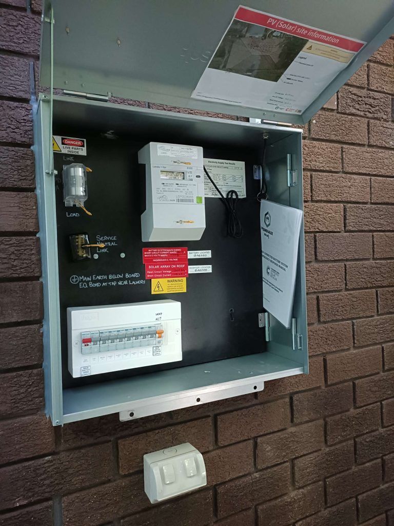 A electrical box is hanging on a brick wall.
