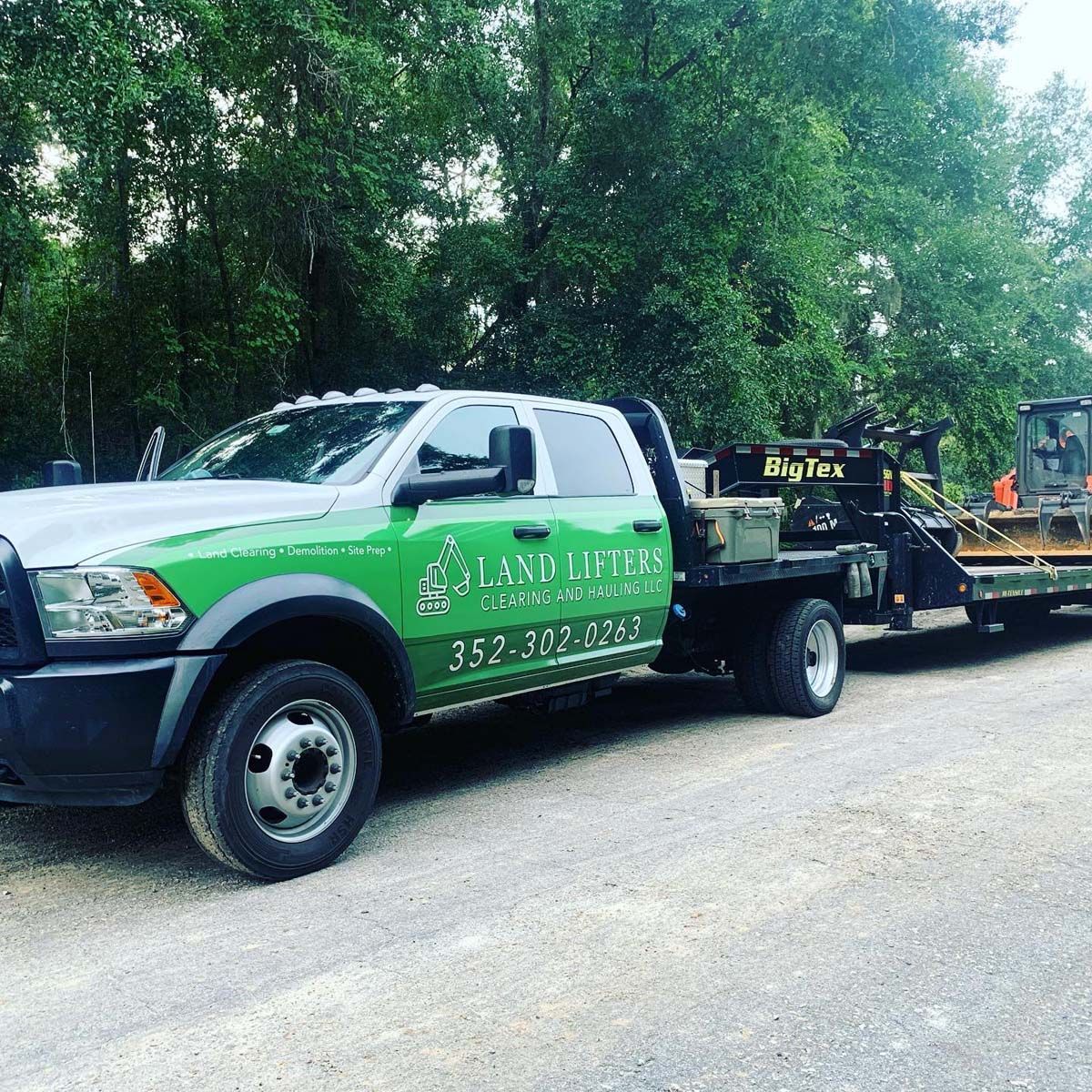 A green and white truck is parked on the side of the road.