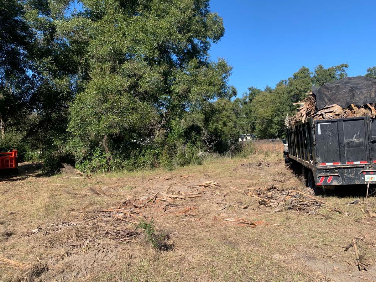 A dump truck is parked in a field with trees in the background.