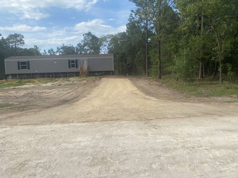 A mobile home is parked on the side of a dirt road.