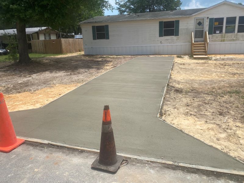 A concrete driveway is being built in front of a mobile home.