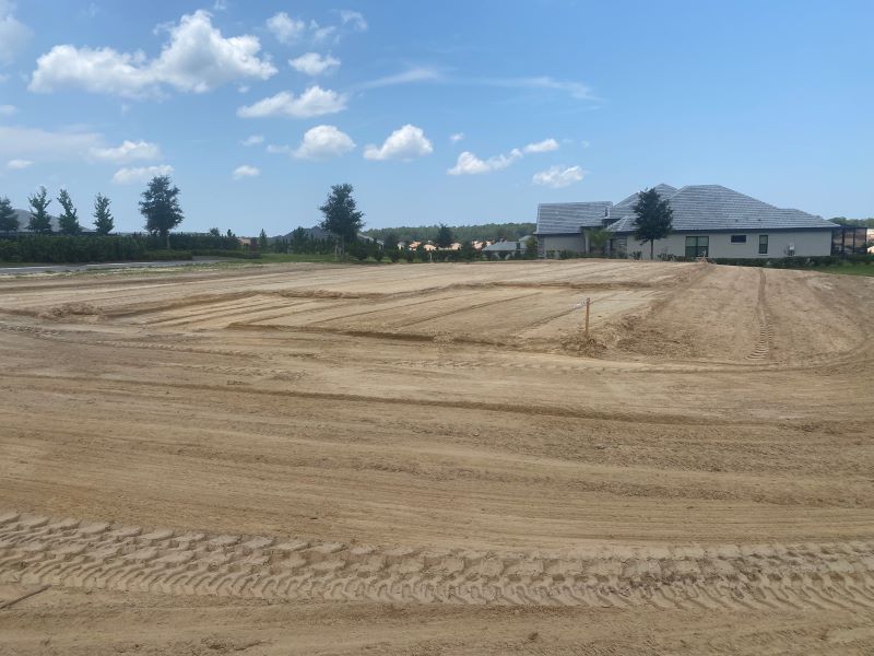 A large dirt field with a house in the background