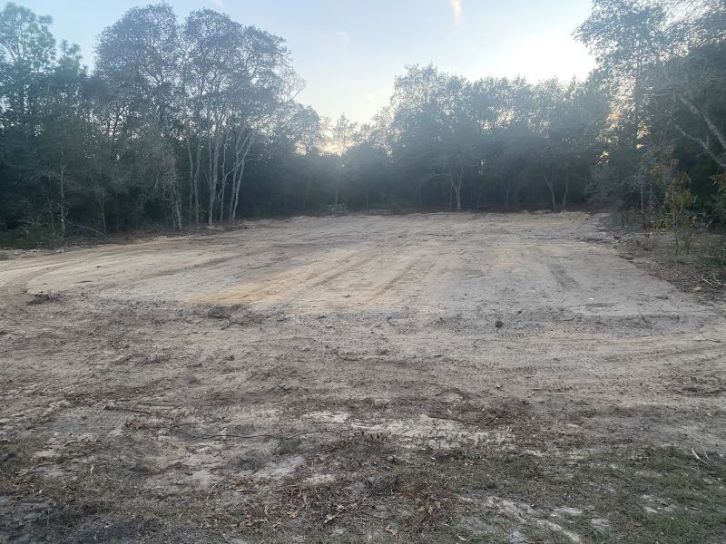A large dirt field with trees in the background.