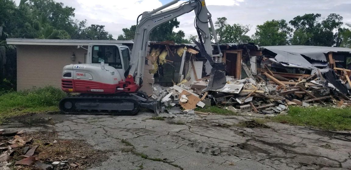 A house is being demolished by an excavator.