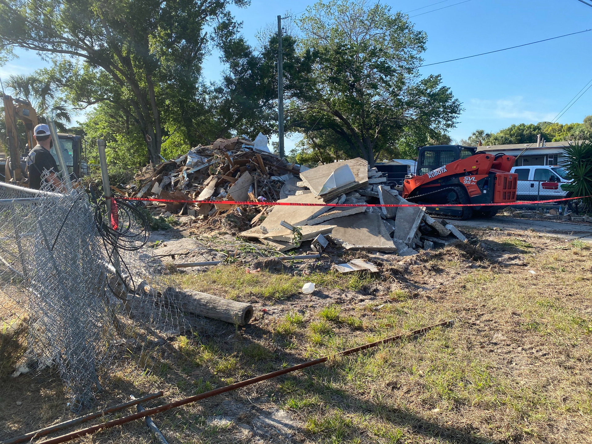 A bulldozer is demolishing a house in a yard.