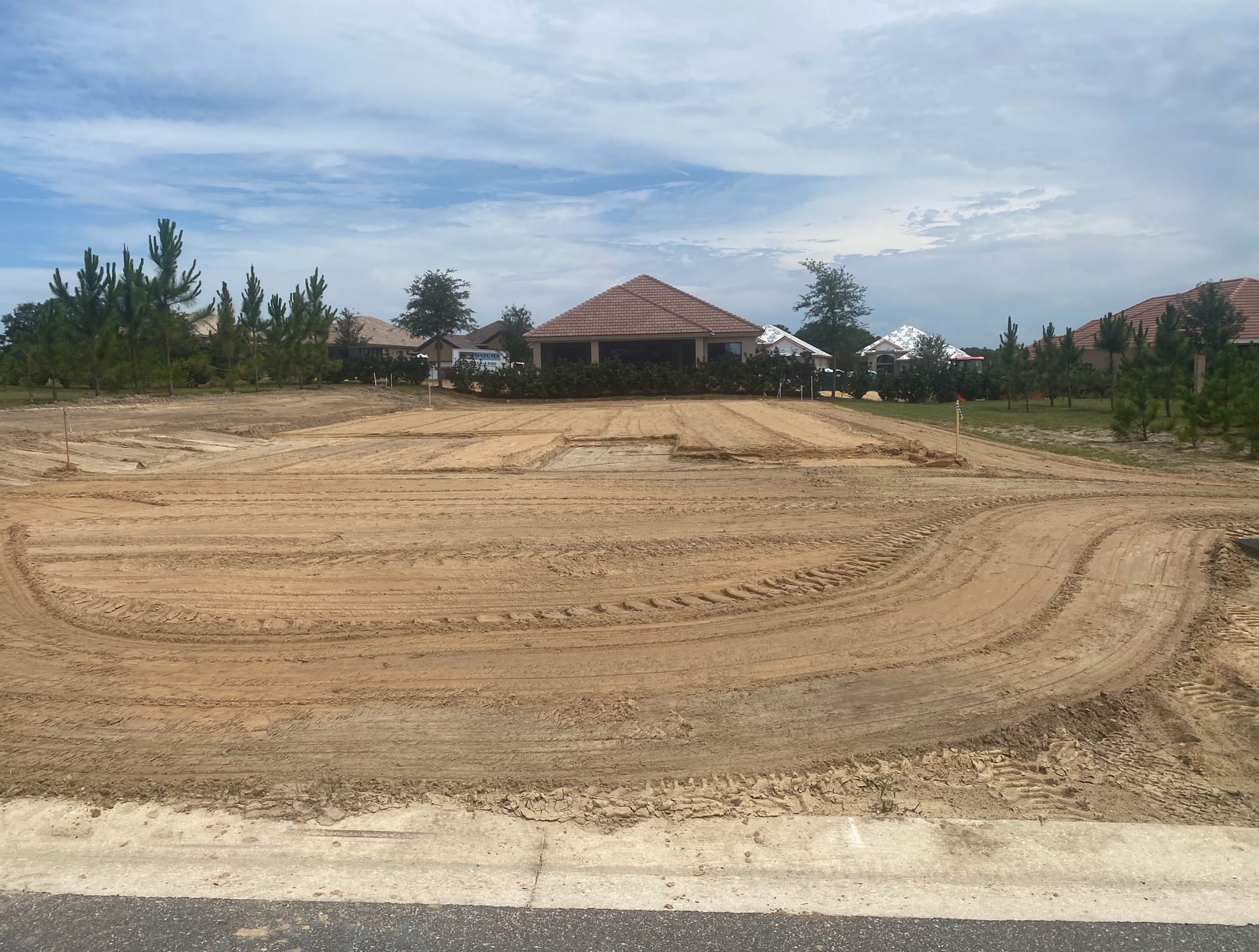 A large dirt field with a house in the background.