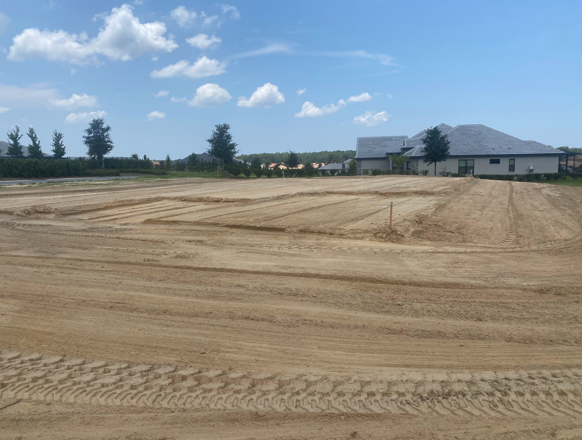 A large dirt field with a house in the background