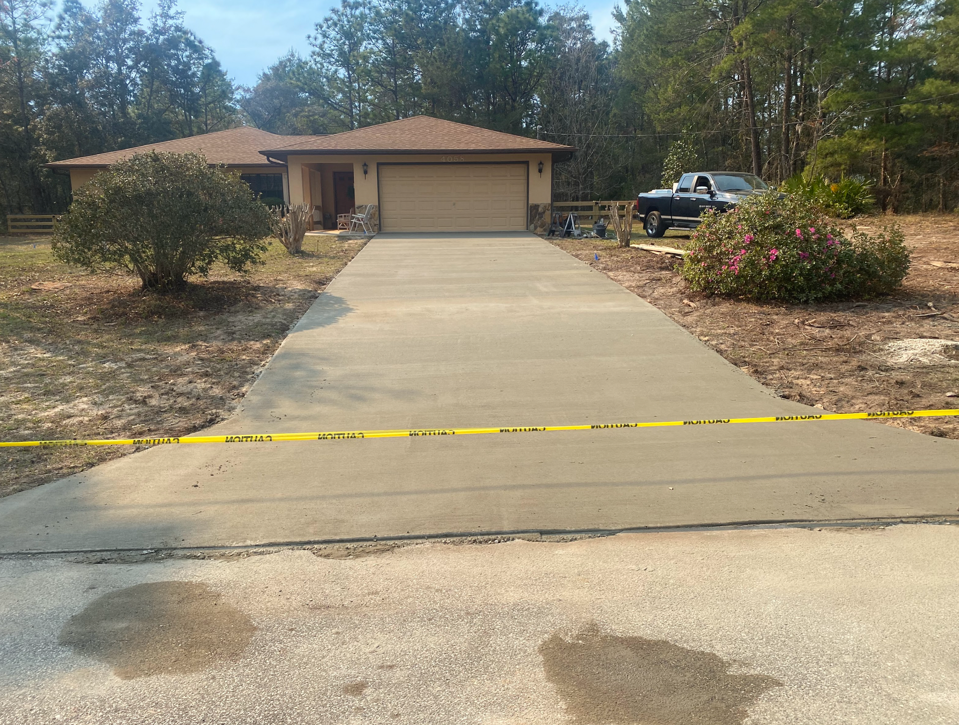 A concrete driveway leading to a house with a truck parked in front of it