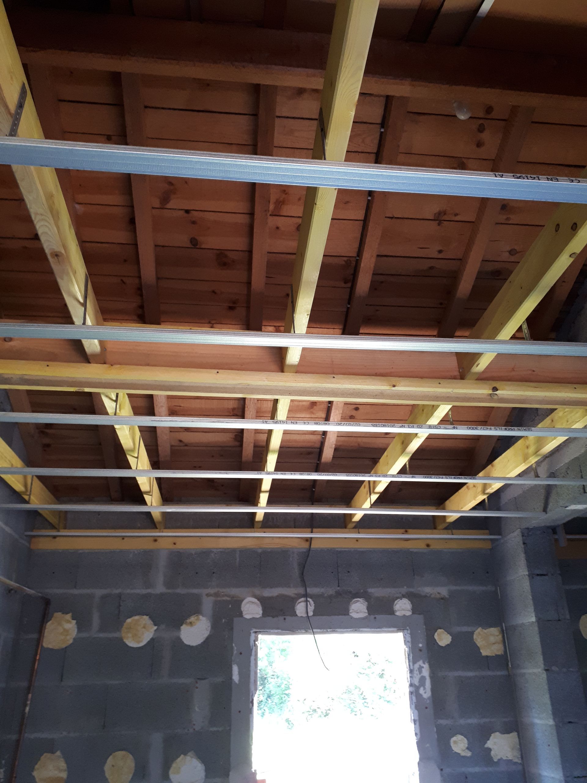 Bâtiment en béton en construction avec échafaudages apparents et supports en bois. La structure comporte plusieurs niveaux.