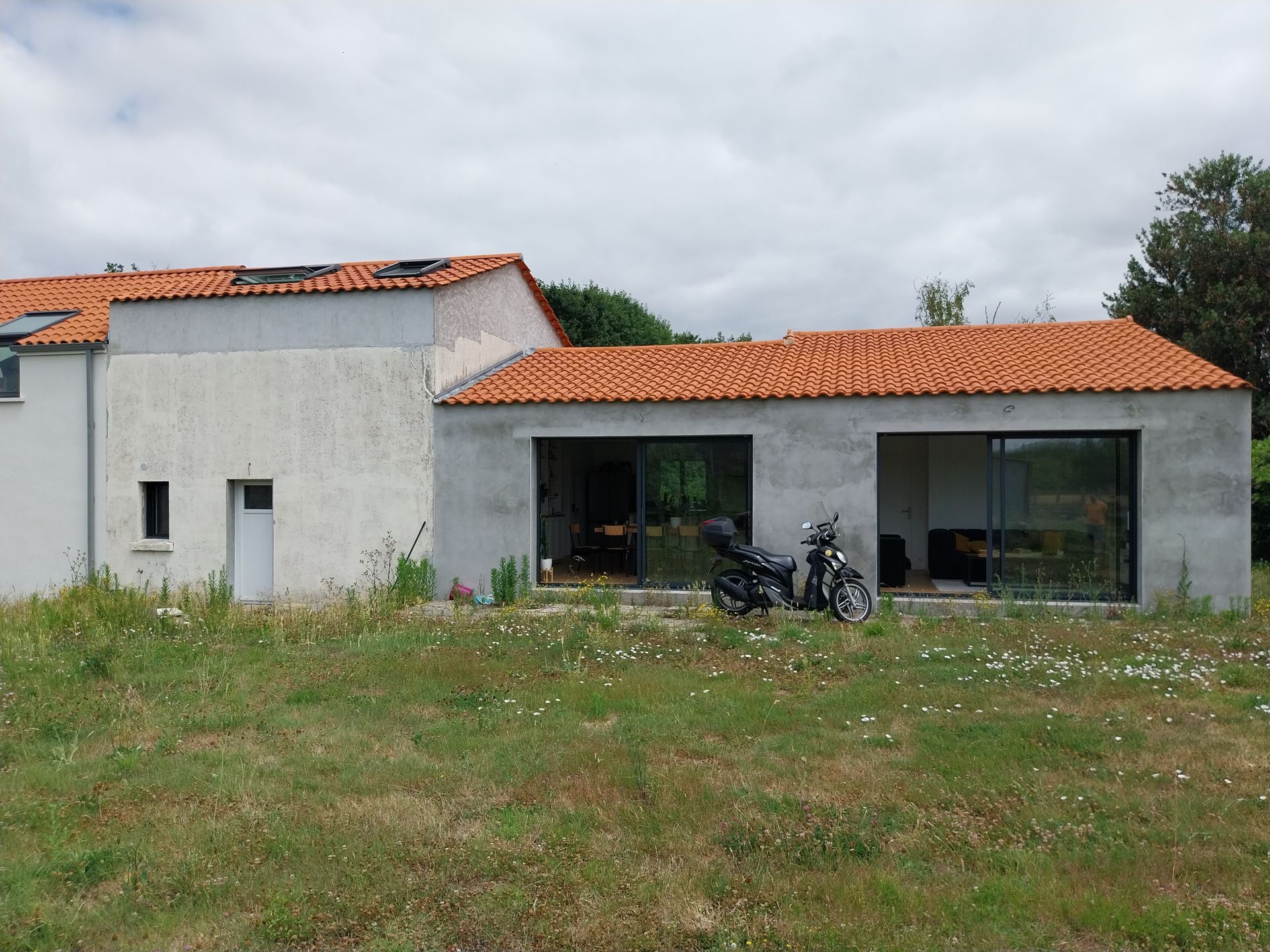 Cuisine avec placards, évier, hotte et crédence carrelée ; un casque repose sur le plan de travail.