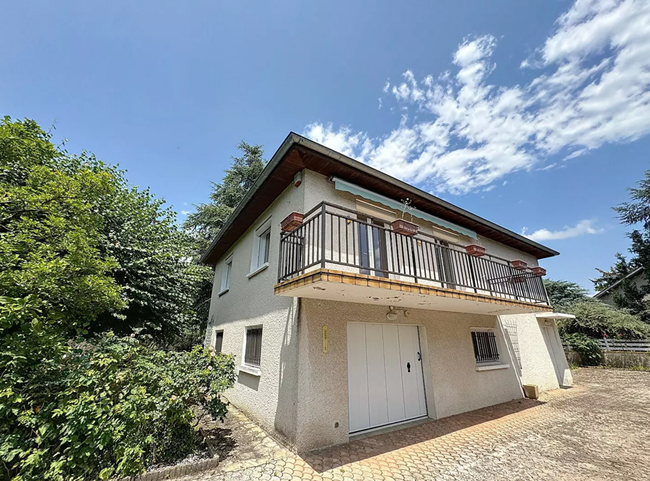 Maison gris clair à deux étages avec des boiseries blanches, un garage double et une allée. 