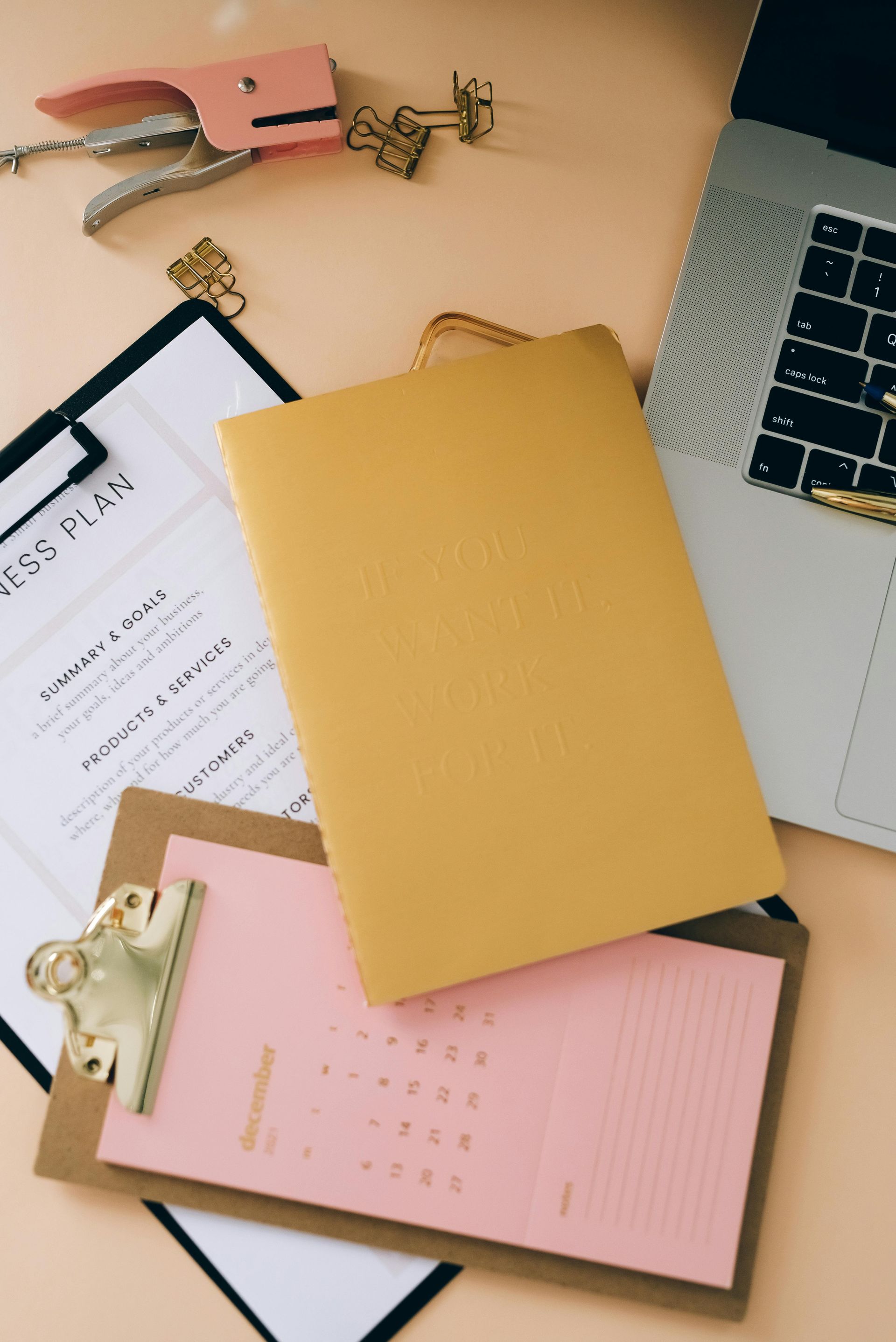 Une personne assise à un bureau utilise une calculatrice, prend des notes et travaille sur un ordinateur portable.