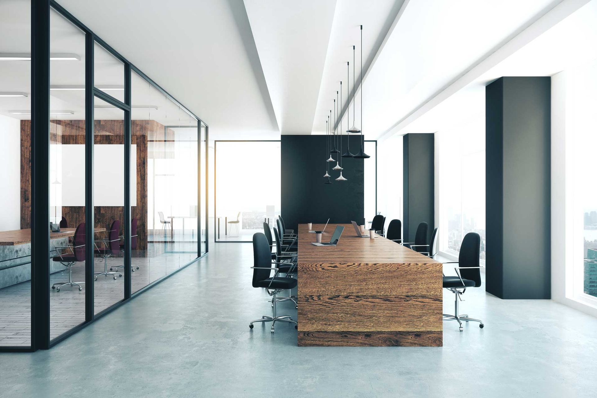 Modern office meeting room with long wooden table, black chairs, and glass walls.