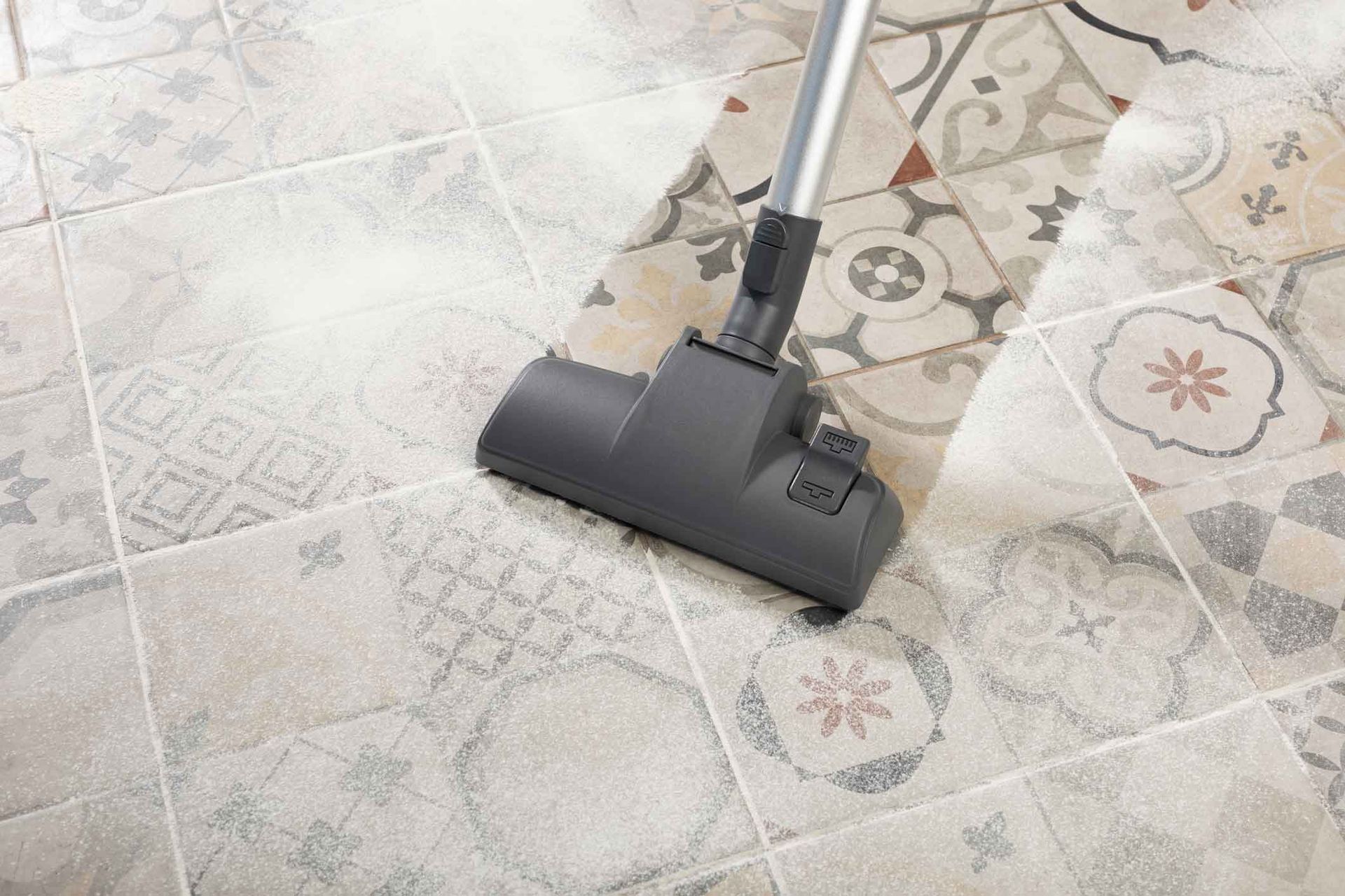 Vacuum cleaner cleaning patterned tile floor.
