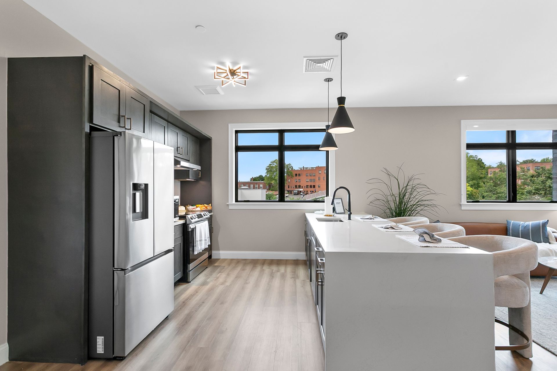 Modern kitchen and dining area with stainless appliances, white island, pendant light, and large windows