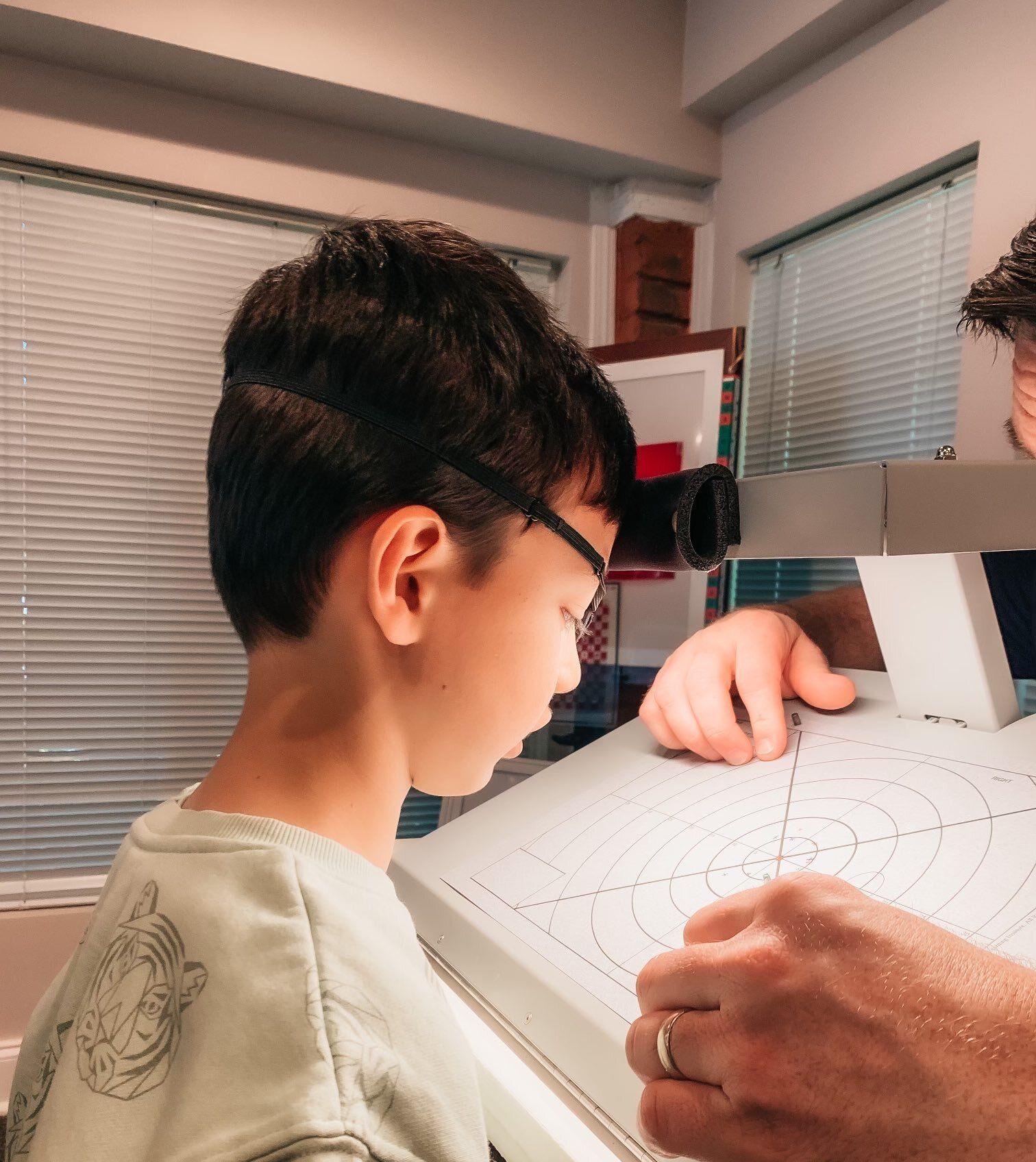 A young boy wearing glasses is looking at a piece of paper