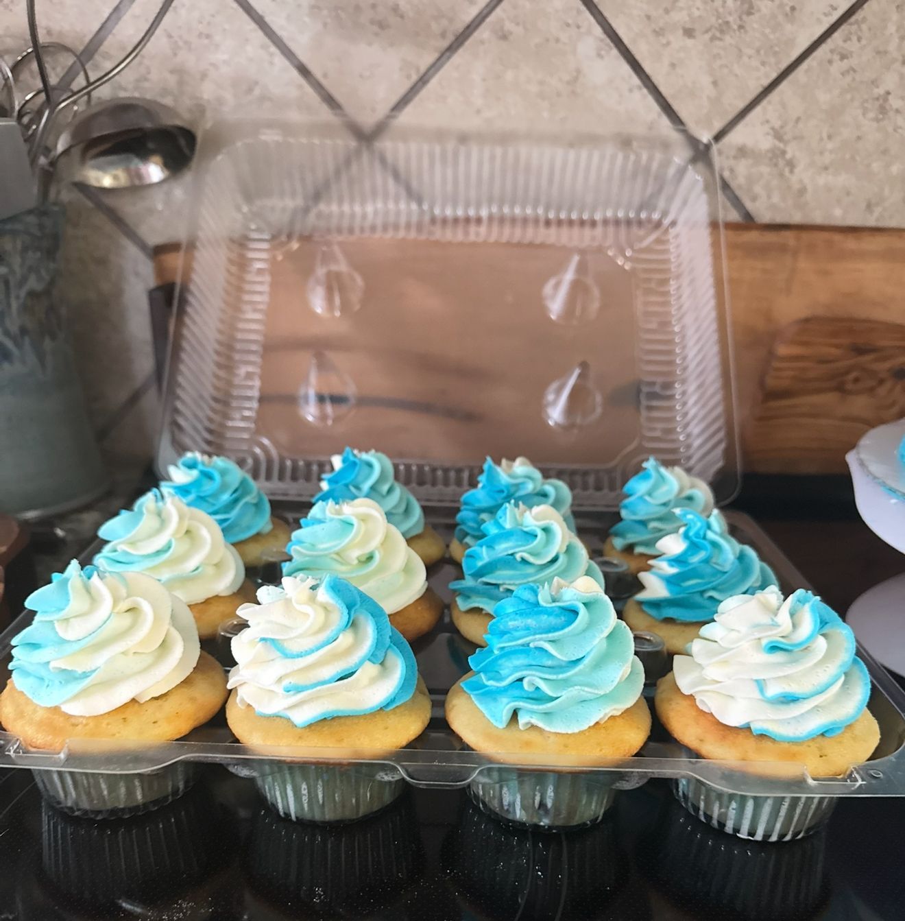 Cupcakes in clear container with blue and white frosting.