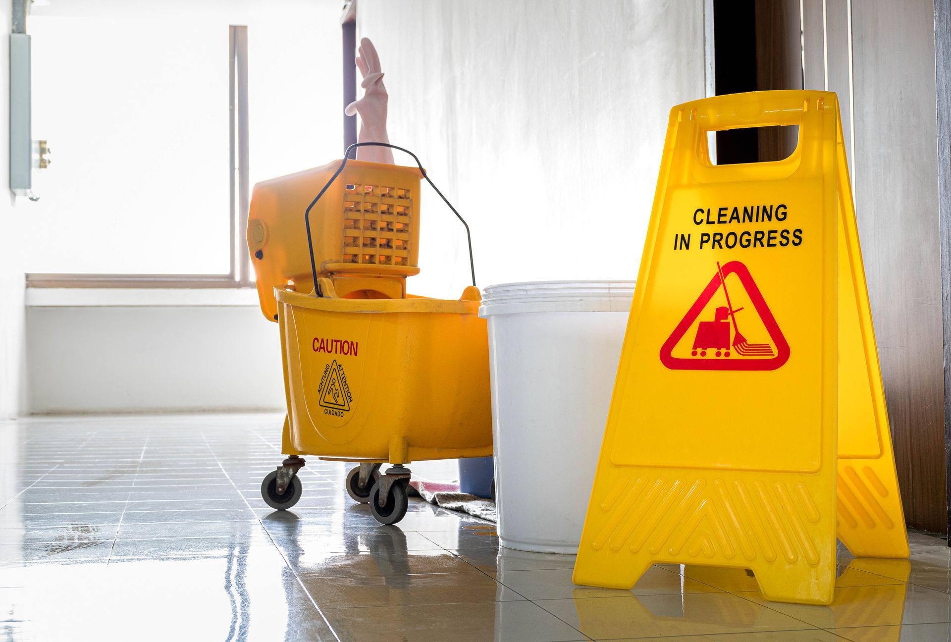 A yellow wet floor sign is next to a mop and bucket.