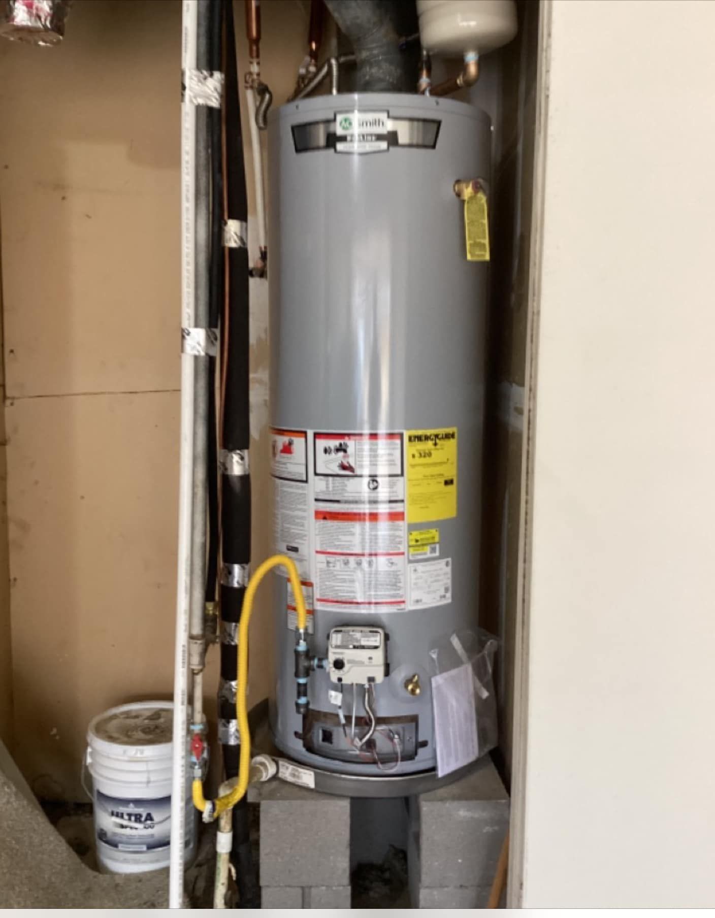 A gas water heater is sitting in a corner of a room.