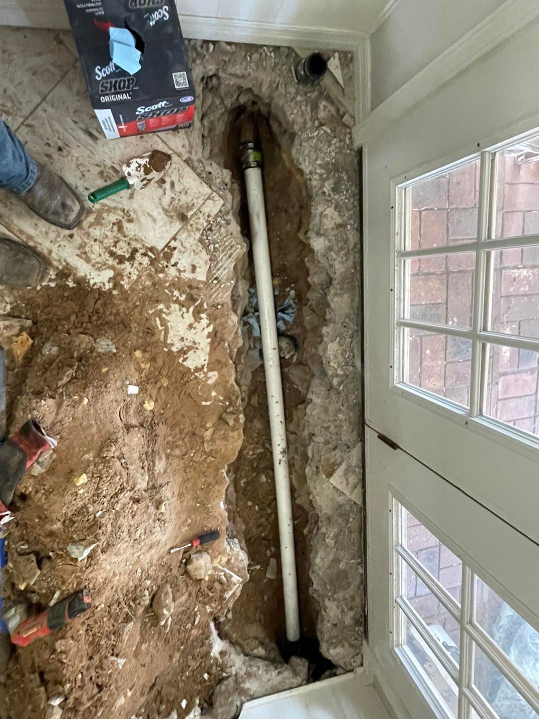 A pipe is being installed in a hole in the floor.