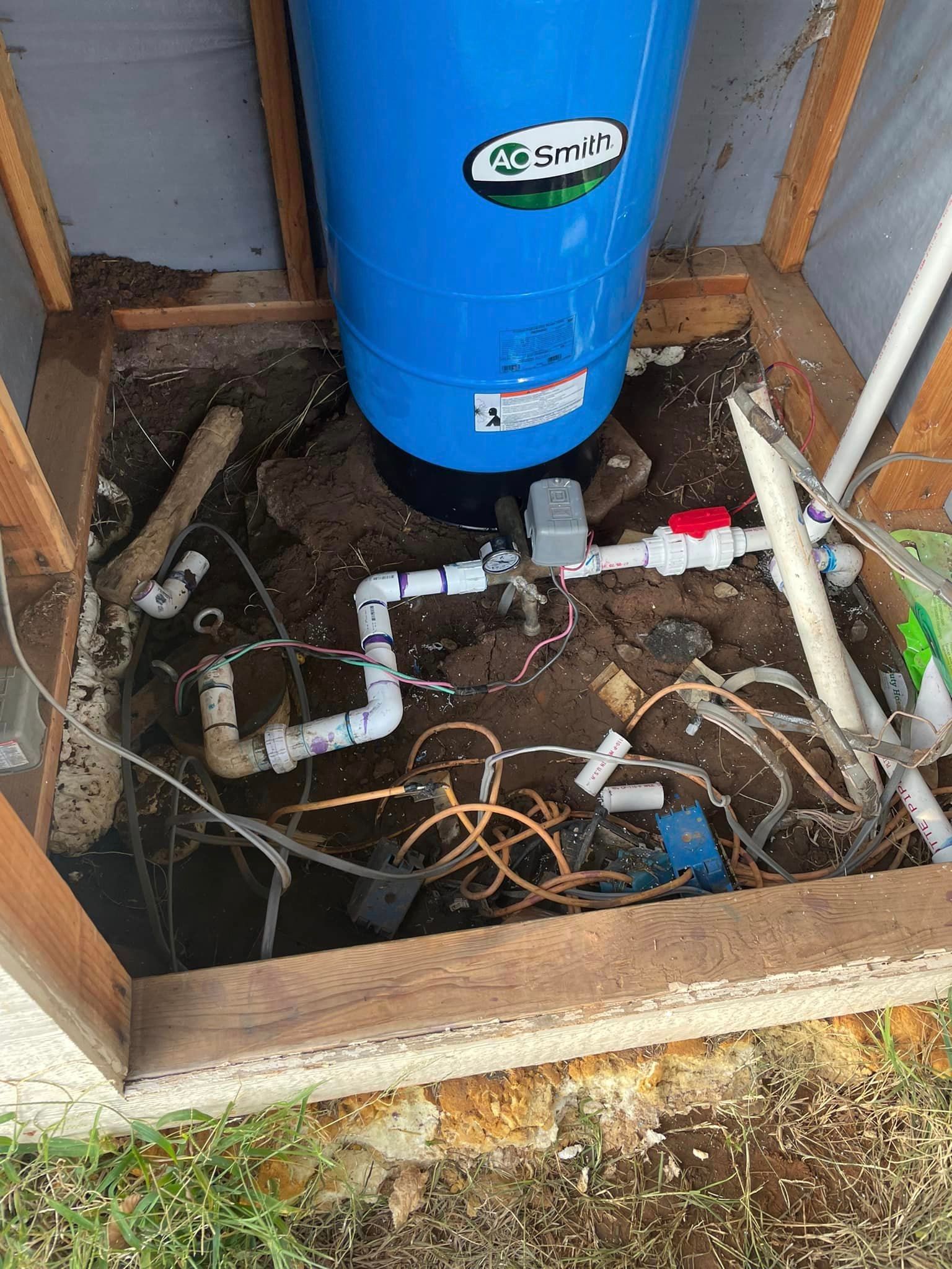 A blue water tank is sitting in the dirt in a shed.