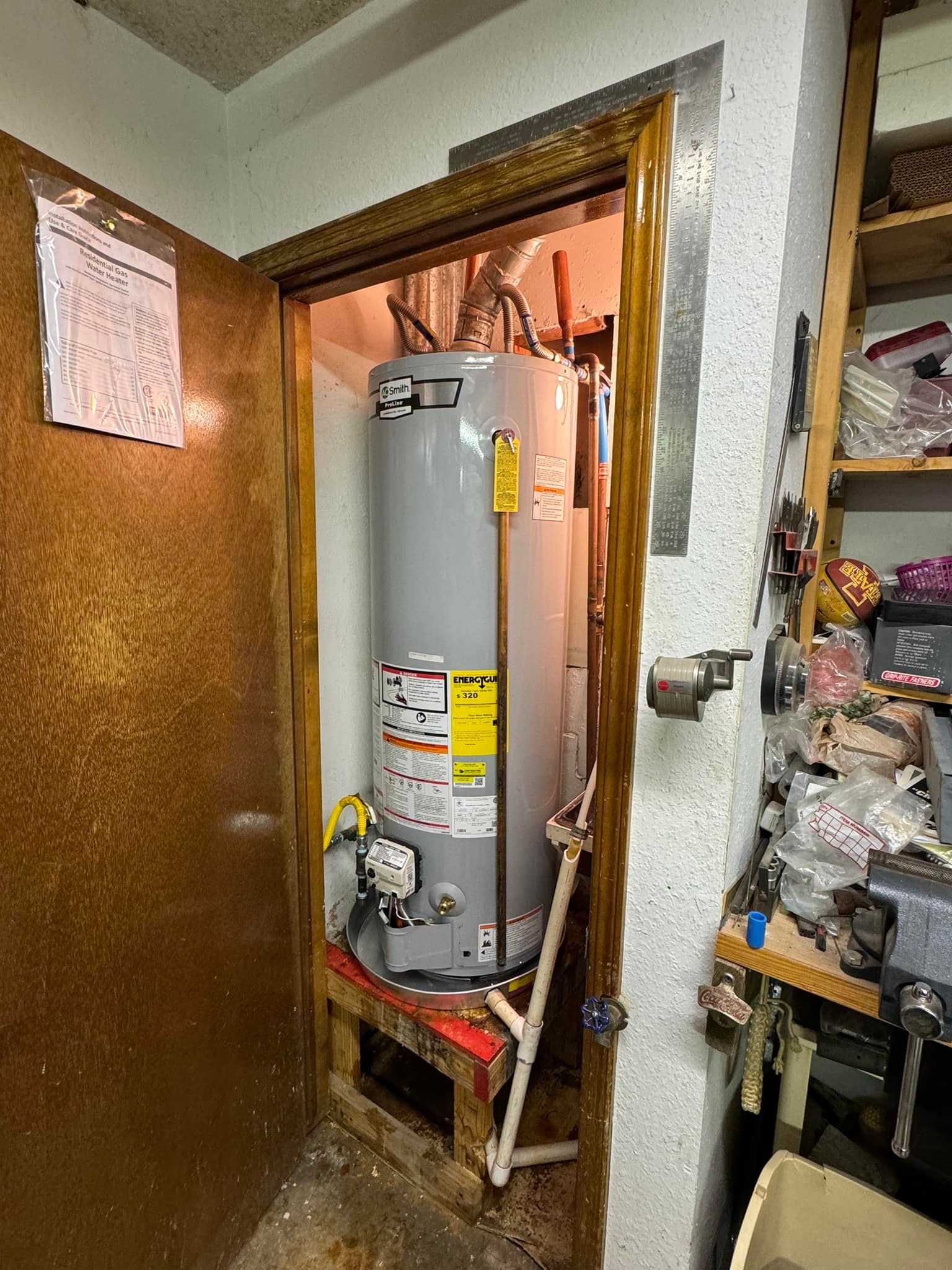 A water heater is sitting inside of a doorway in a room.