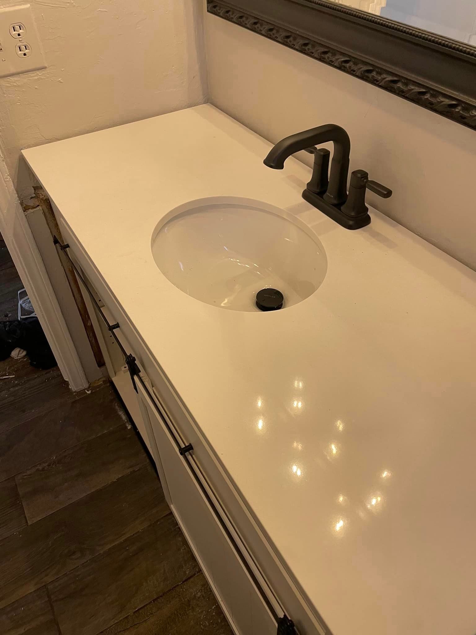 A bathroom sink with a black faucet and a white counter top.