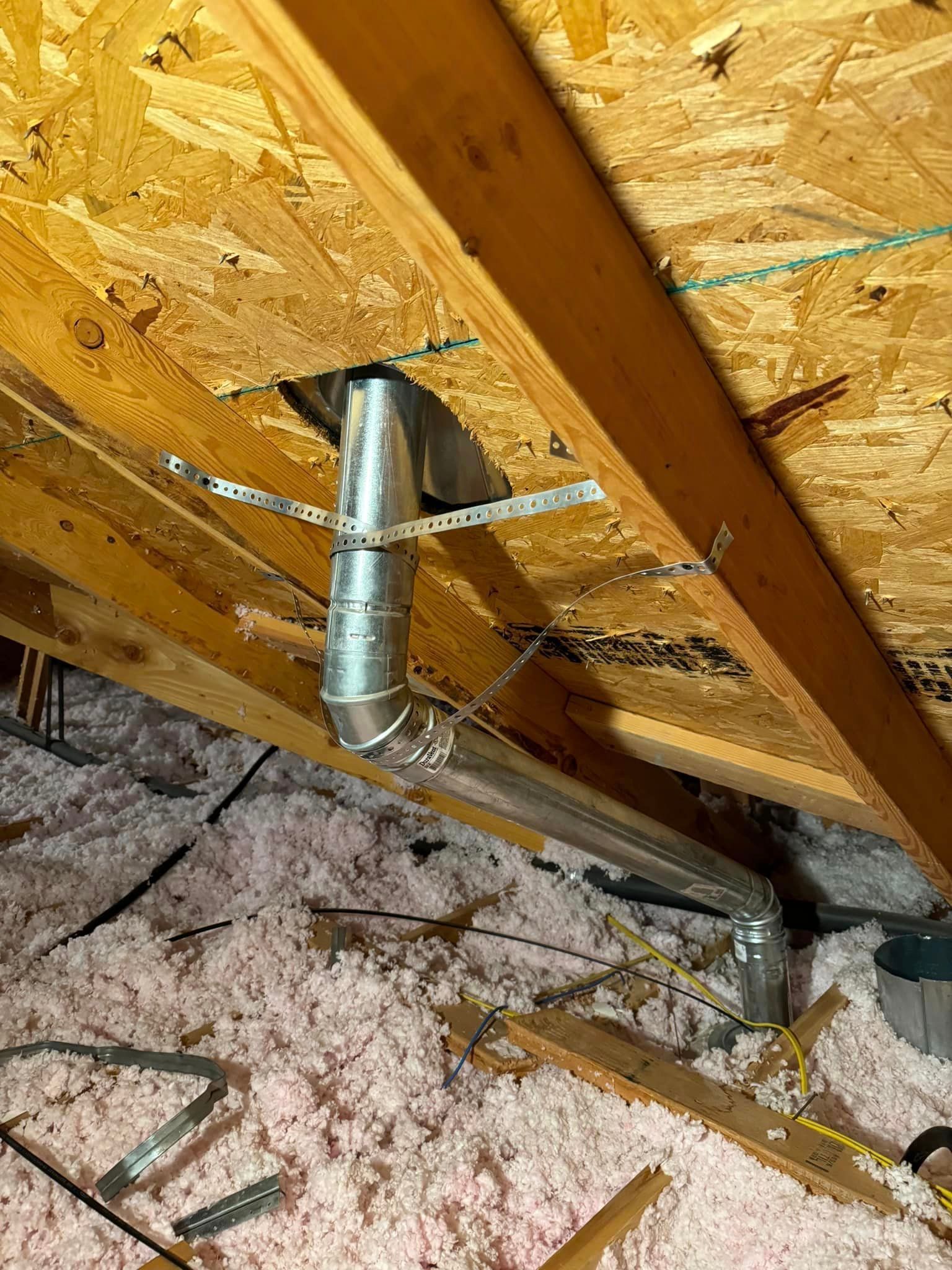 A metal pipe is hanging from the ceiling of an attic.