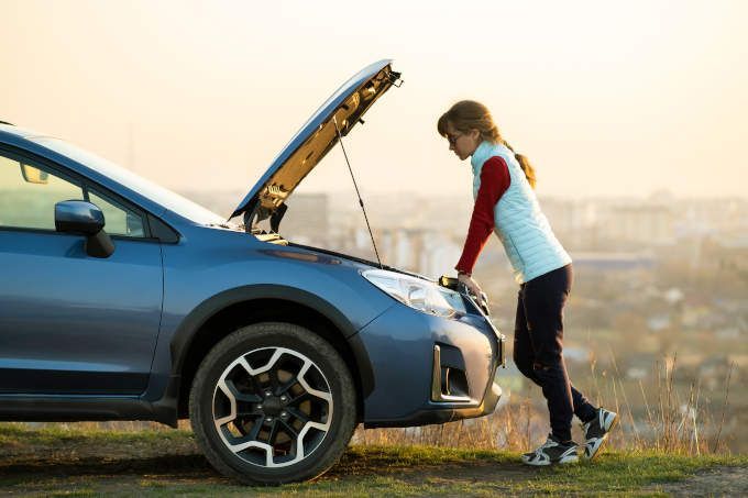 Woman looking under the hood of her car
