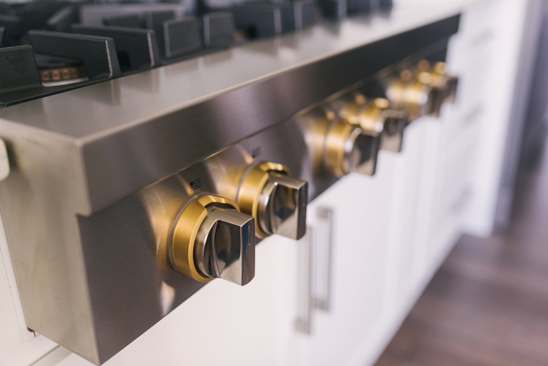 A stainless steel stove top oven with gold knobs in a kitchen.