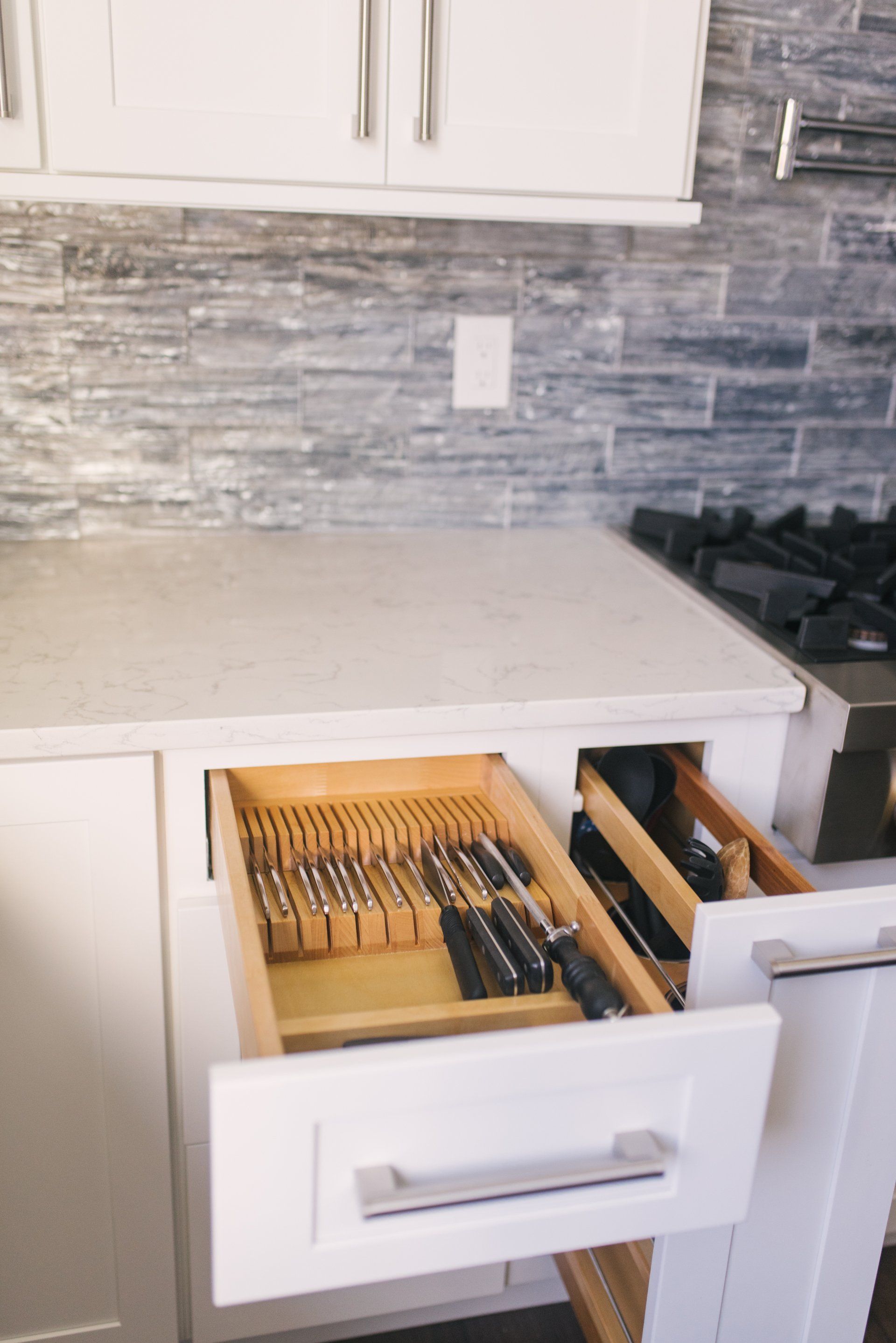 A kitchen with a drawer filled with knives and forks.