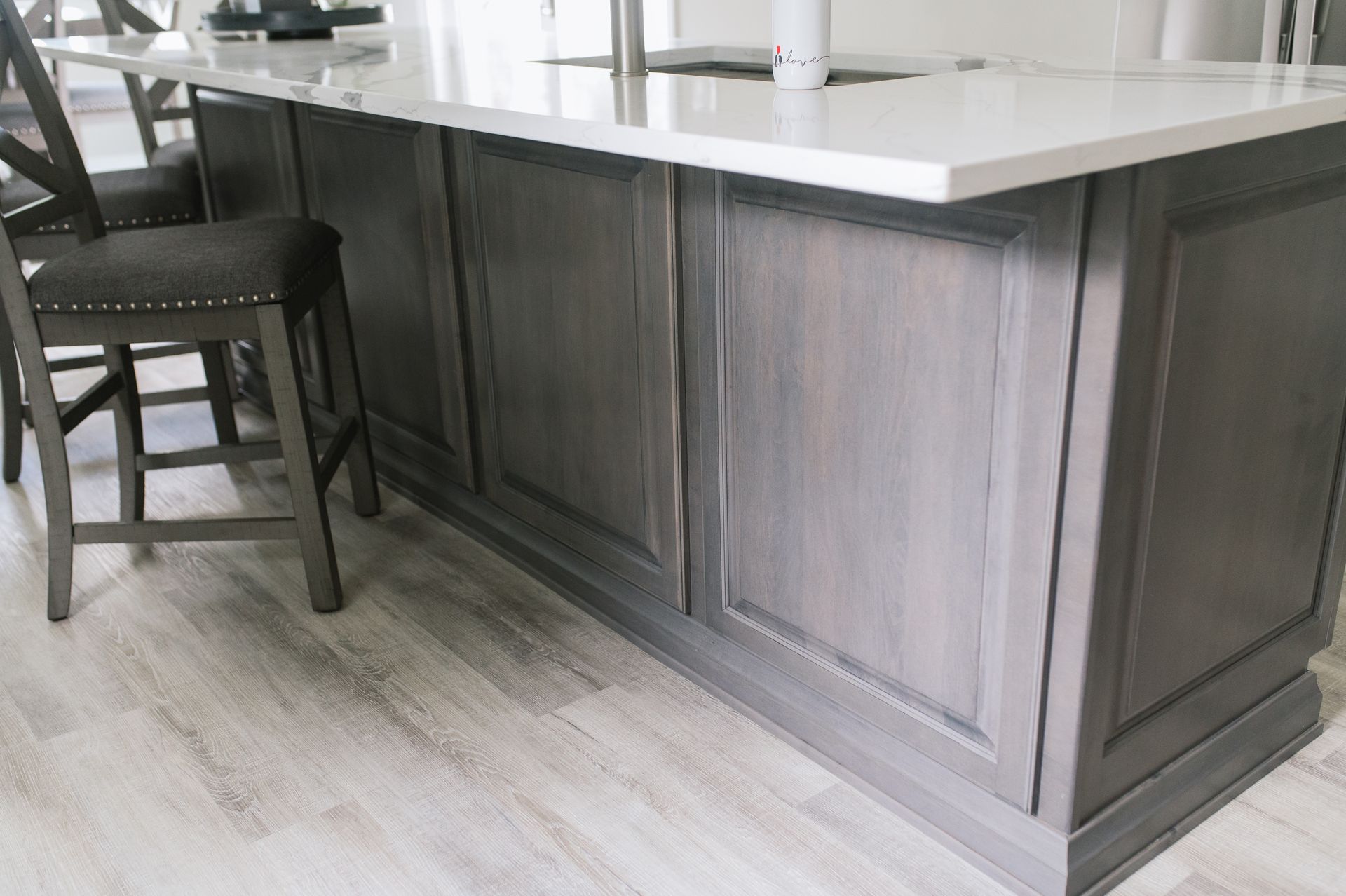 A kitchen island with gray cabinets and a white counter top.