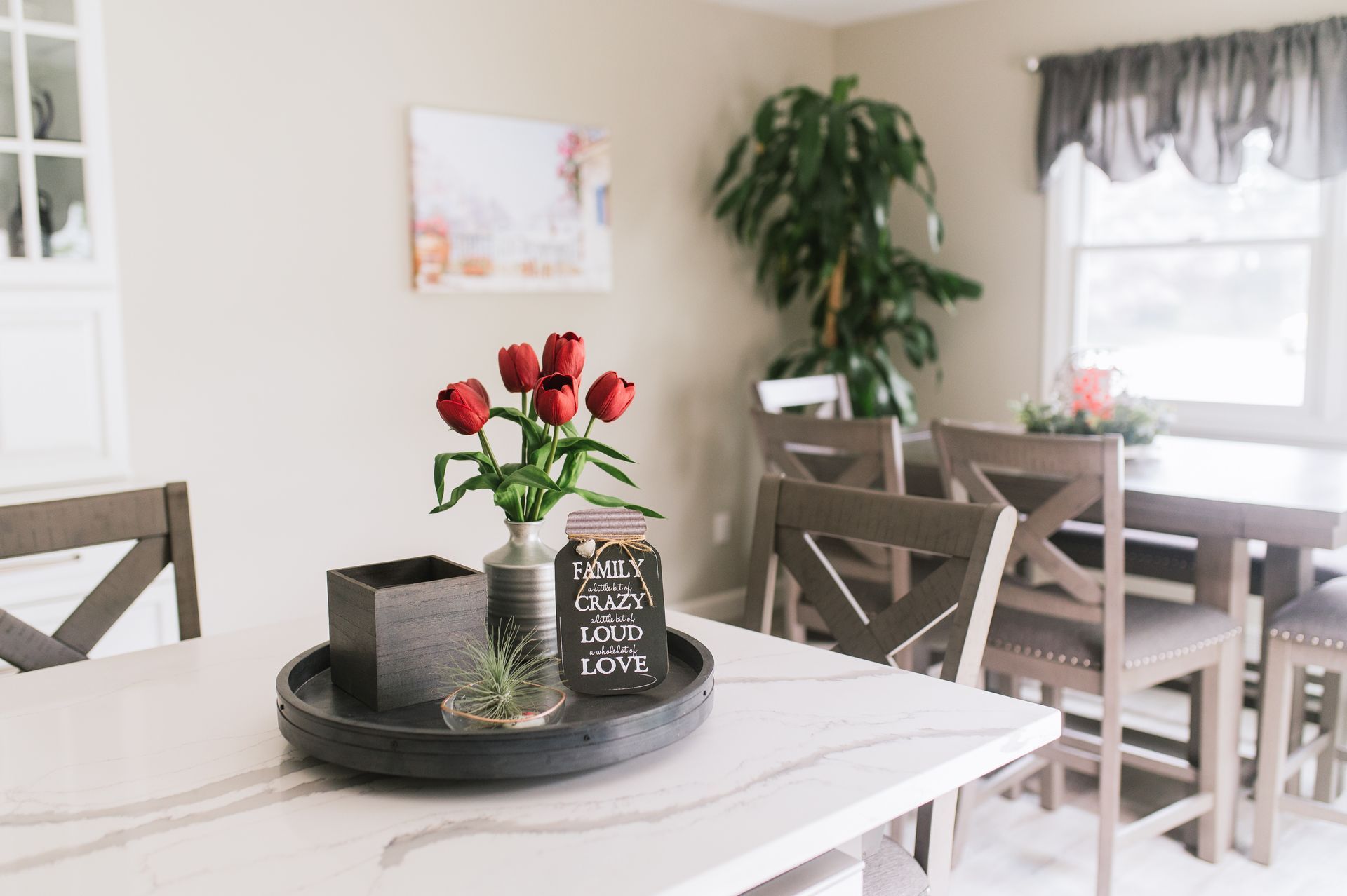 A dining room table with a vase of flowers on it.