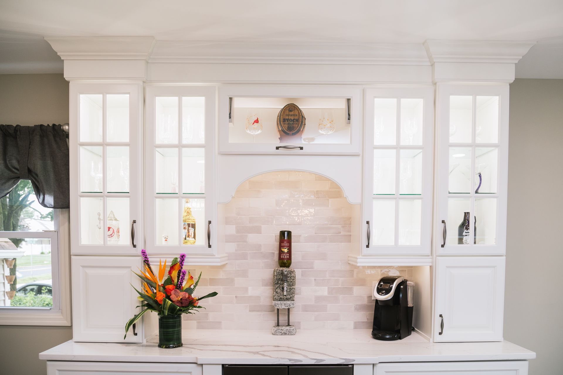 There is a vase of flowers on the counter in the kitchen.
