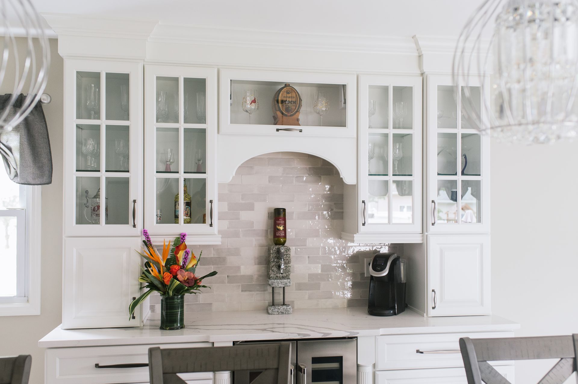 A kitchen with white cabinets and a vase of flowers on the counter.