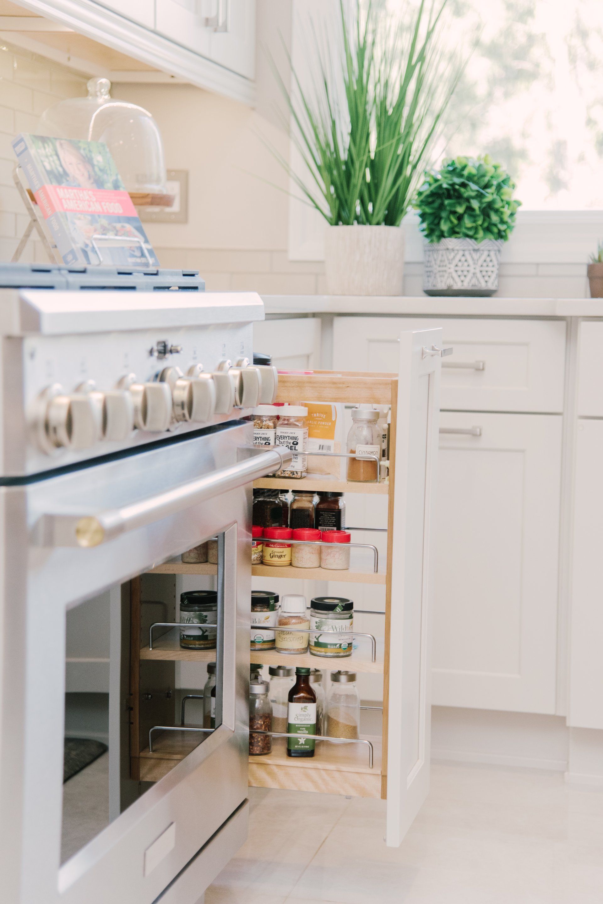 A kitchen with a stove and a pull out spice rack.