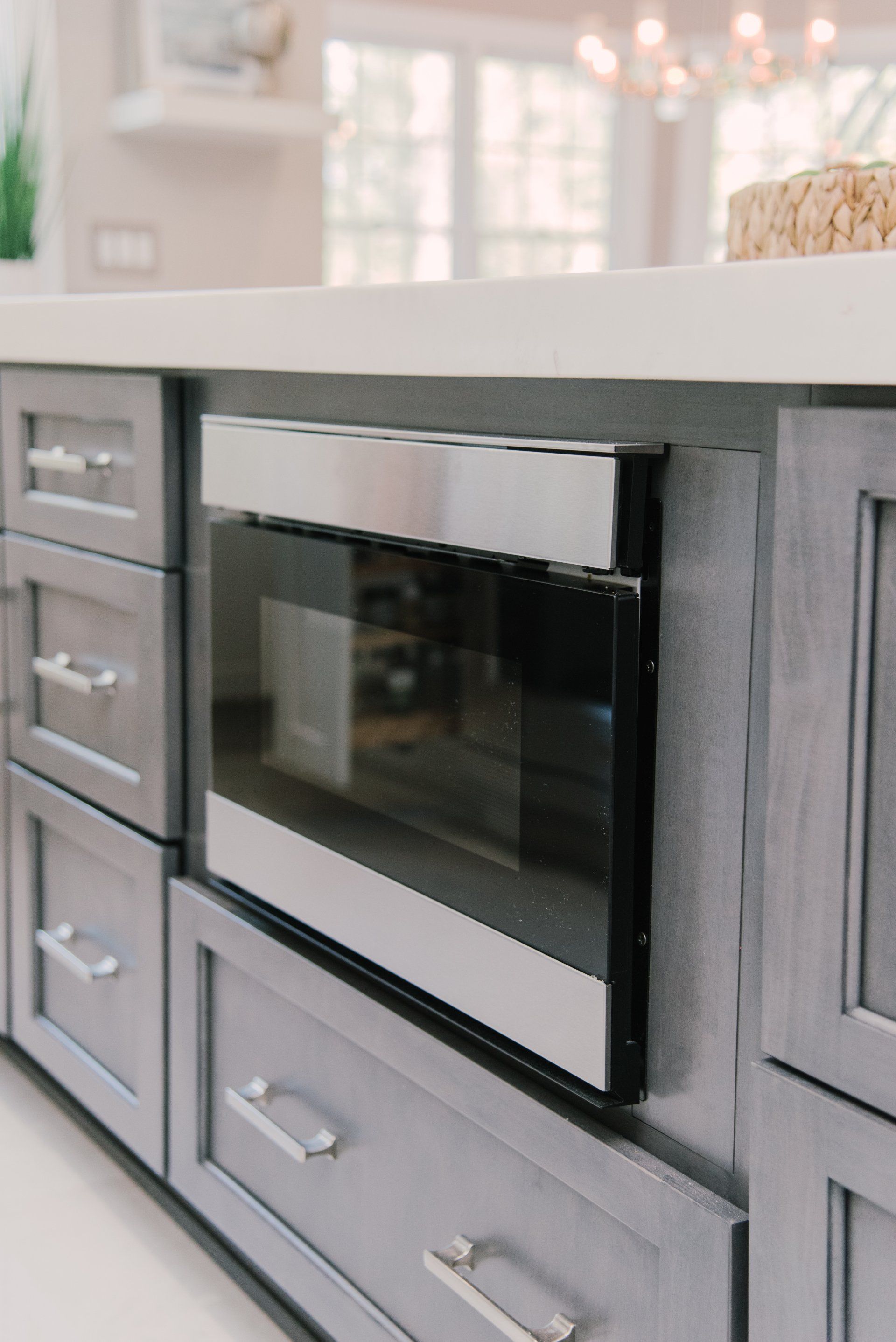A kitchen with gray cabinets and a microwave oven