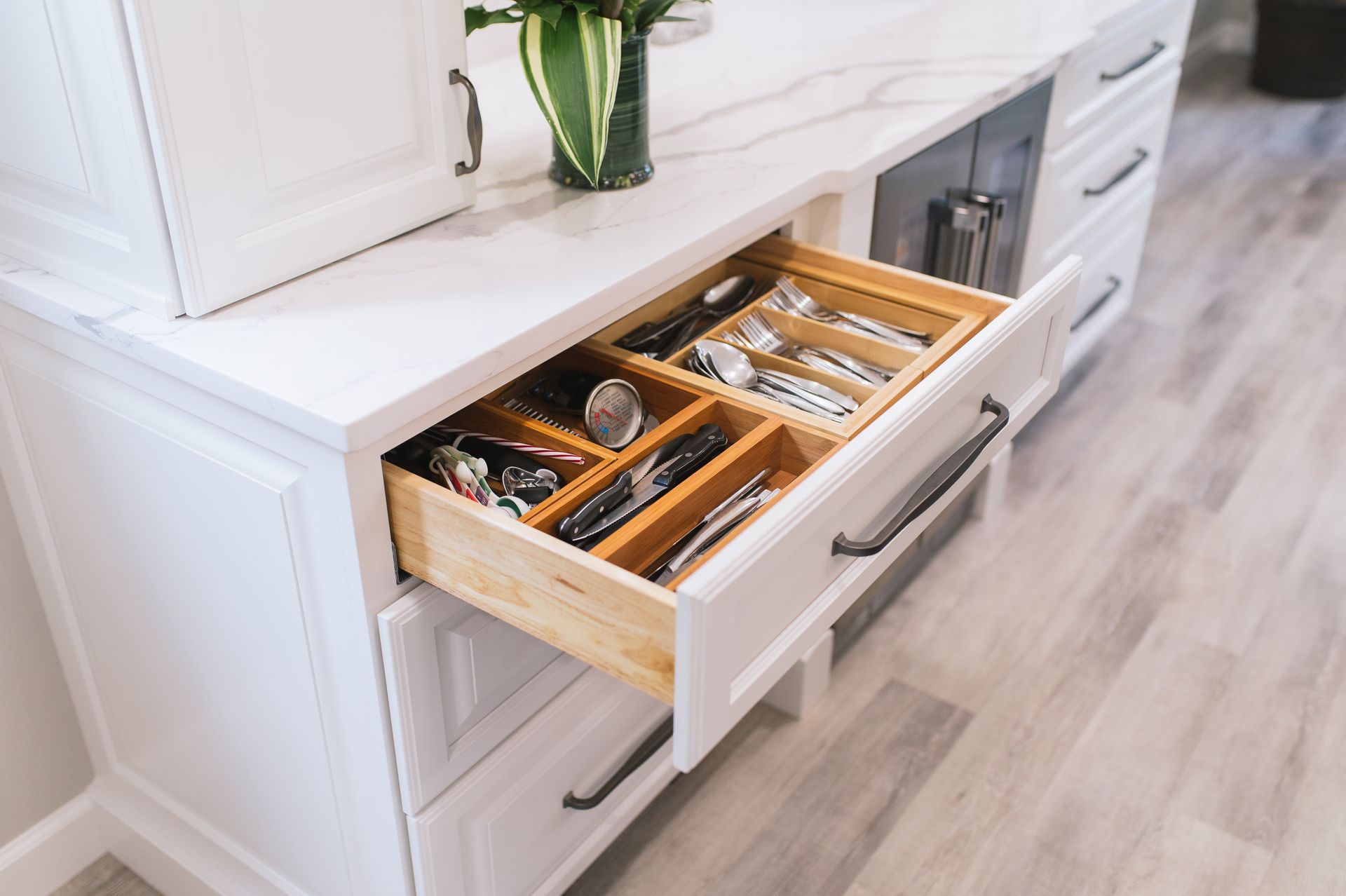 A kitchen dresser with a drawer open filled with silverware.