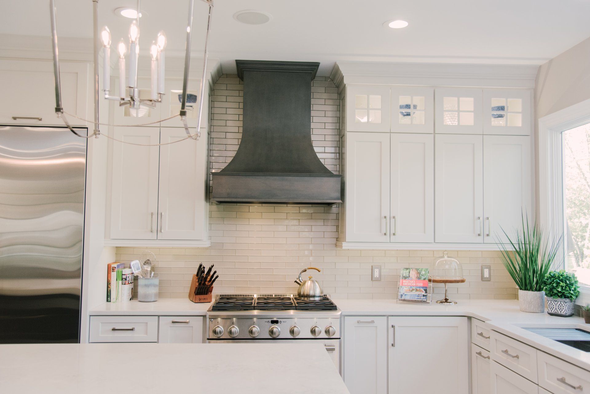 A kitchen with white cabinets , stainless steel appliances , a stove and a hood.