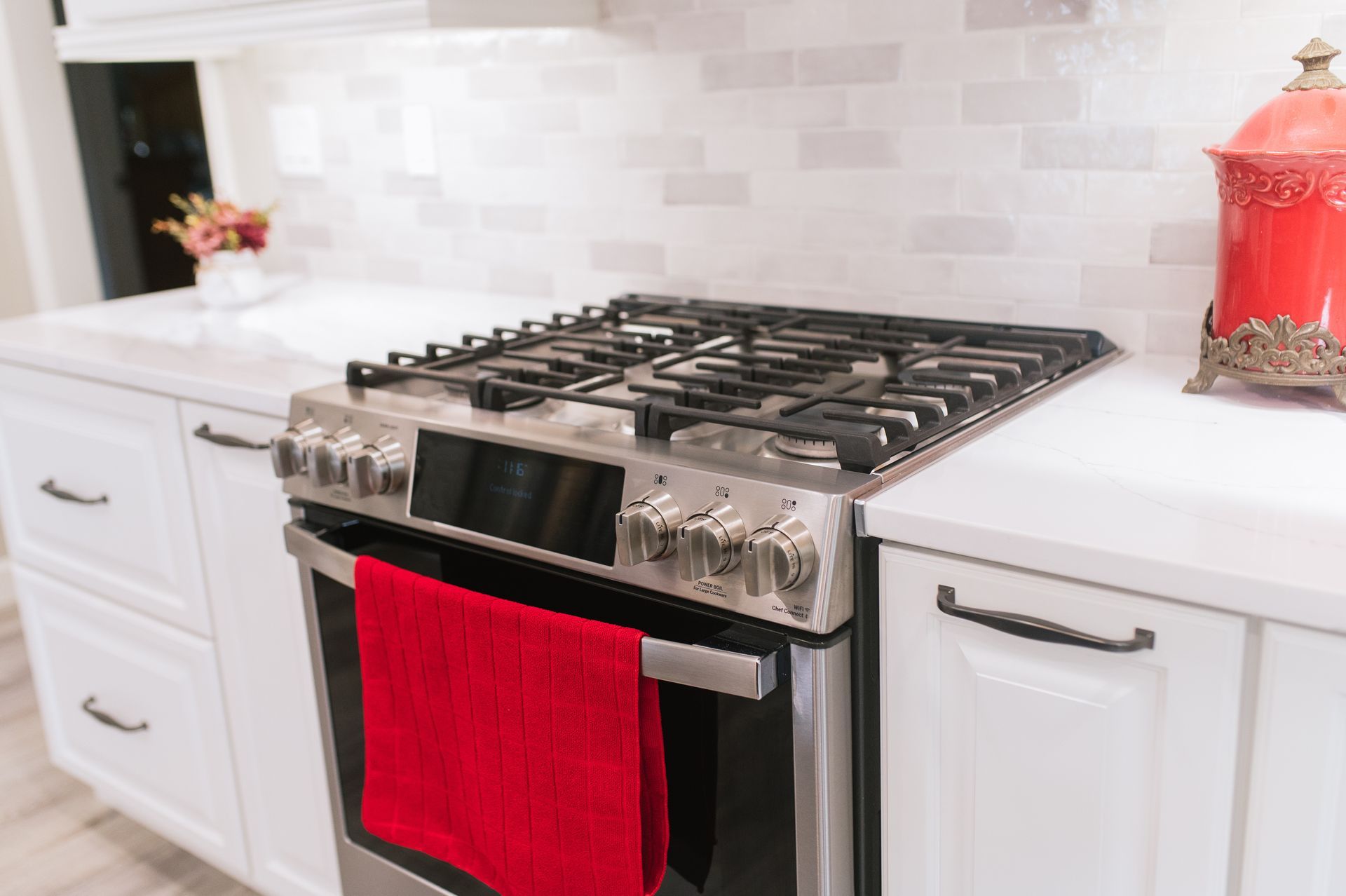 A stove with a red towel hanging out of it in a kitchen.