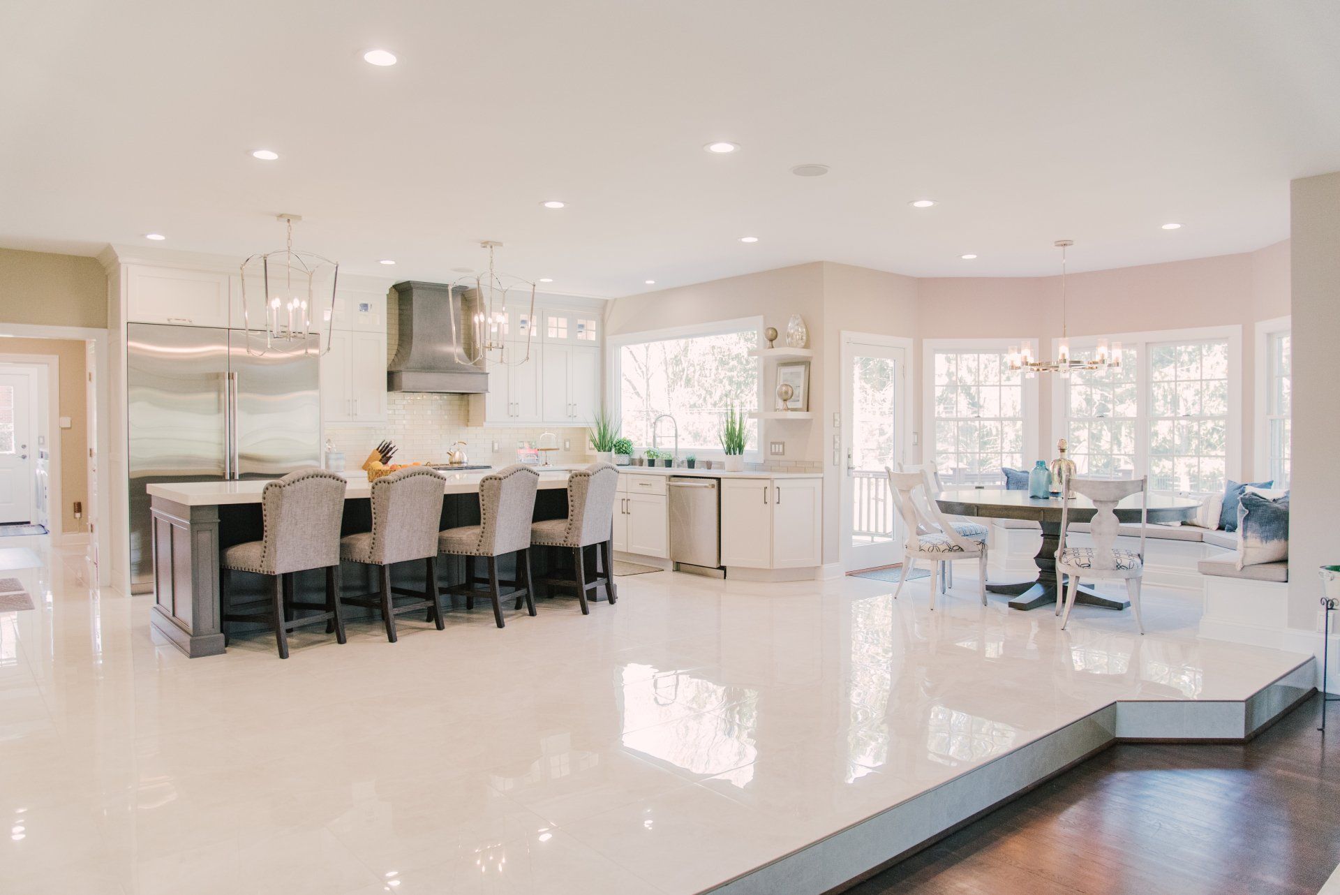 A large kitchen with white cabinets , stainless steel appliances , and a large island.