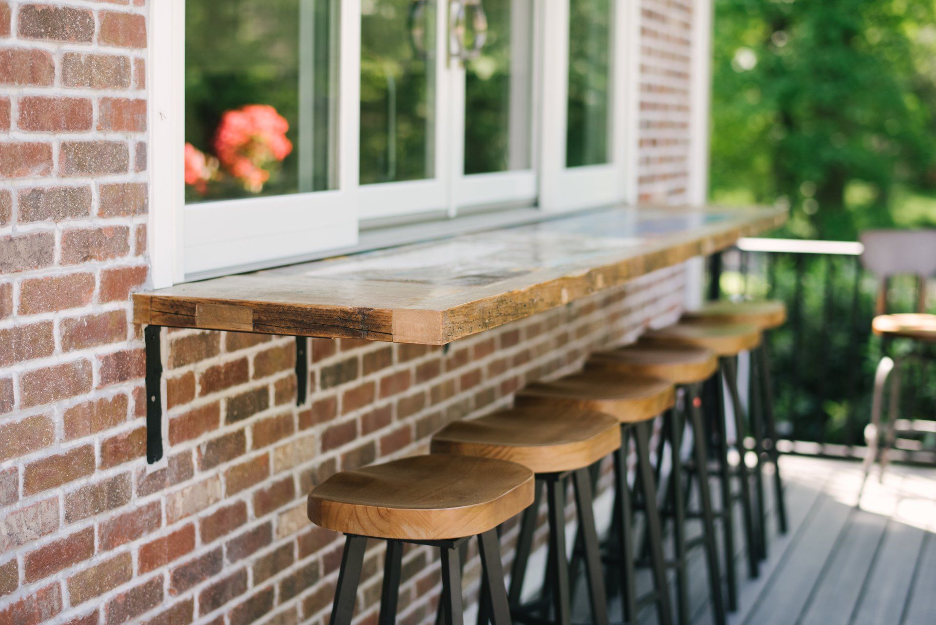 A row of bar stools are lined up against a brick wall.